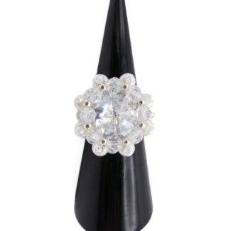 Sparkling crystal cluster ring with large center stone, surrounding clear AB crystals, white pearls, and silver accents on a ring cone. Shown against a white background