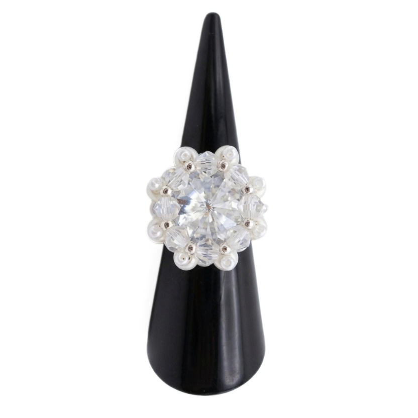 Sparkling crystal cluster ring with large center stone, surrounding clear AB crystals, white pearls, and silver accents on a ring cone. Shown against a white background
