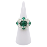 Emerald green crystal ring with white pearl and silver beaded design on white ring display, shown against a white background
