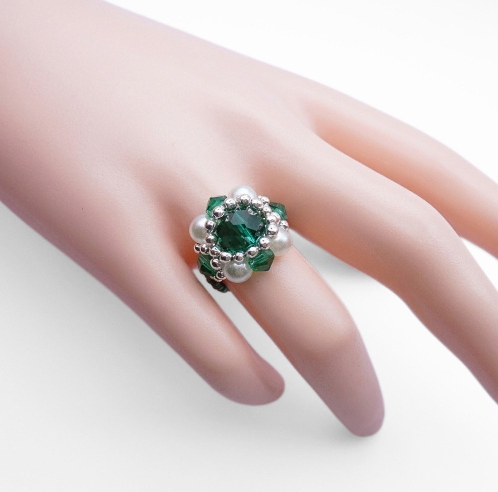 emerald-crystal-ring-hand-display Emerald green crystal ring with white pearl beading worn on hand mannequin, close-up view