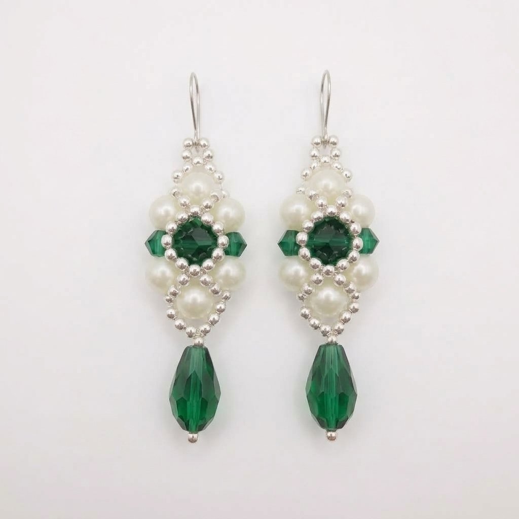 emerald-green-crystal-pearl-earrings Handcrafted drop earrings made with deep emerald green crystals, white pearl beads, and silver accents hanging against a neutral background.