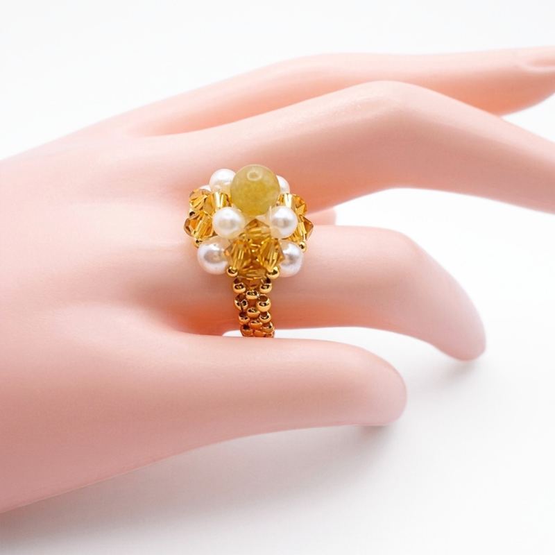 golden-tourmaline-crystal-ring-display Handmade cocktail ring featuring golden crystals, white pearls, and a gold-toned tourmaline stone displayed on a mannequin hand model.