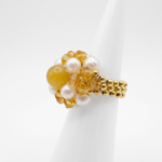 A side view of a cocktail ring with golden faceted crystals, cream pearls and golden tourmaline centre bead, handcrafted statement jewellery