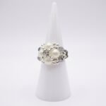 White pearl and smoky grey crystal beaded cocktail ring with silver accents, displayed on a ring cone - side view.