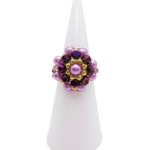 Purple crystal and pearl cocktail ring with gold accents, a handcrafted statement jewellery piece shown on a white display stand against a white background.