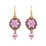 Pair of elegant purple pearl and crystal earrings with luminous lavender pearls, faceted plum-purple crystals, gold-coloured accents and dangling pearl drops on a white background.