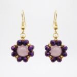 Rose quartz flower earrings with metallic purple crystal beads and gold-tone hooks, shown against a neutral background.
