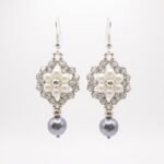 Pair of elegant silver pearl and crystal earrings with soft ivory pearls, faceted silver-grey crystals, silver-coloured accents and dangling grey pearl drops on a white background.