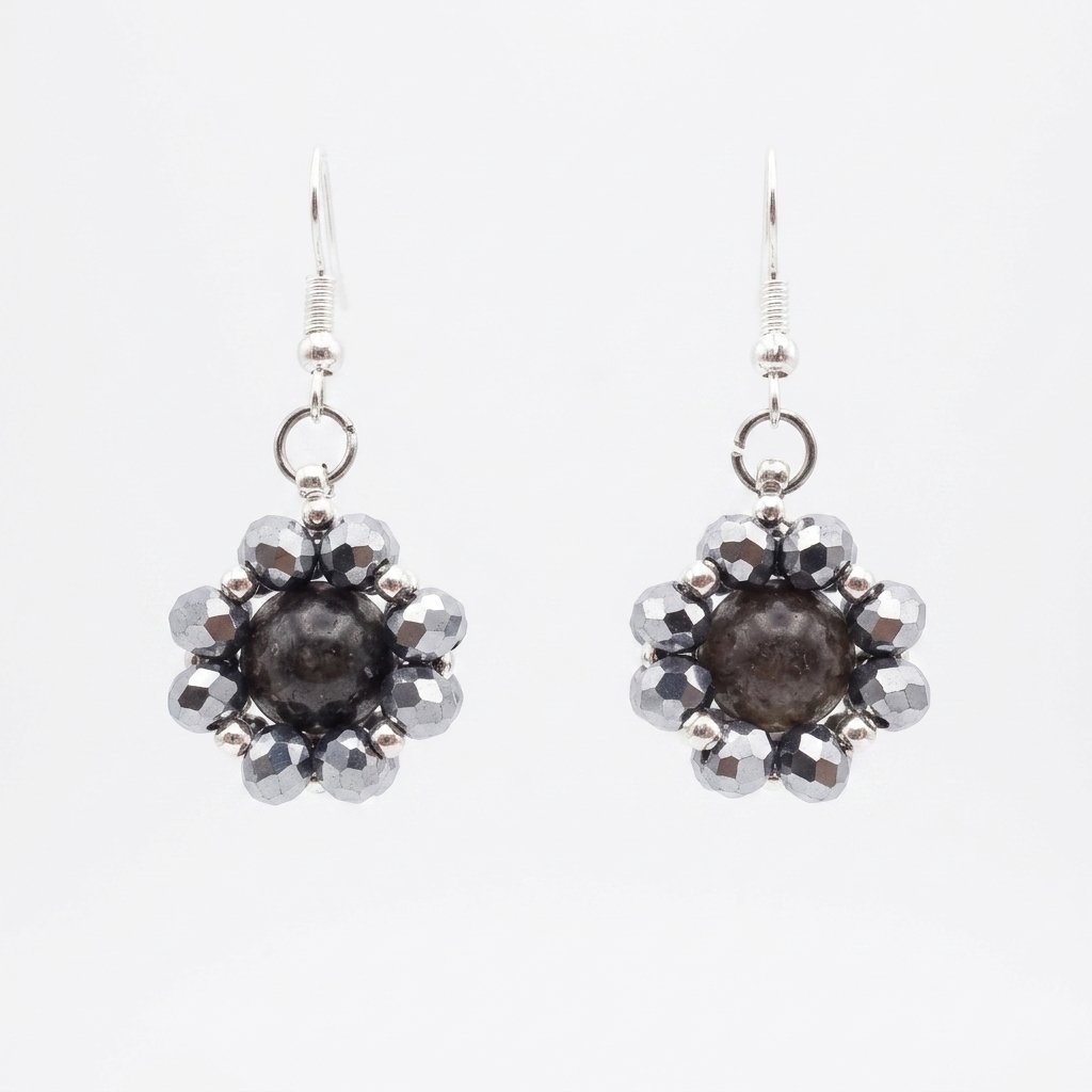 toumaline-silver-crystal-earrings Dark grey tourmaline gemstone centre surrounded by shimmering metallic silver crystals and silver hooks, shown against a neutral background.