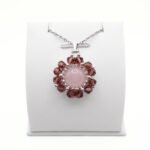 Handmade rose quartz and purple crystal flower pendant necklace with silver-tone beads on a silver chain, displayed on a white jewellery stand