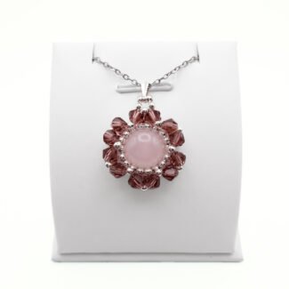 Handmade rose quartz and purple crystal flower pendant necklace with silver-tone beads on a silver chain, displayed on a white jewellery stand