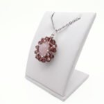 A side view of a rose quartz and purple crystal flower pendant necklace with silver accents on silver chain - displayed on a white jewellery stand